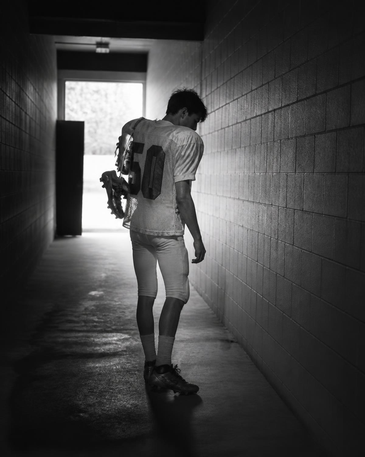 A young athlete walking alone down a tunnel after a game