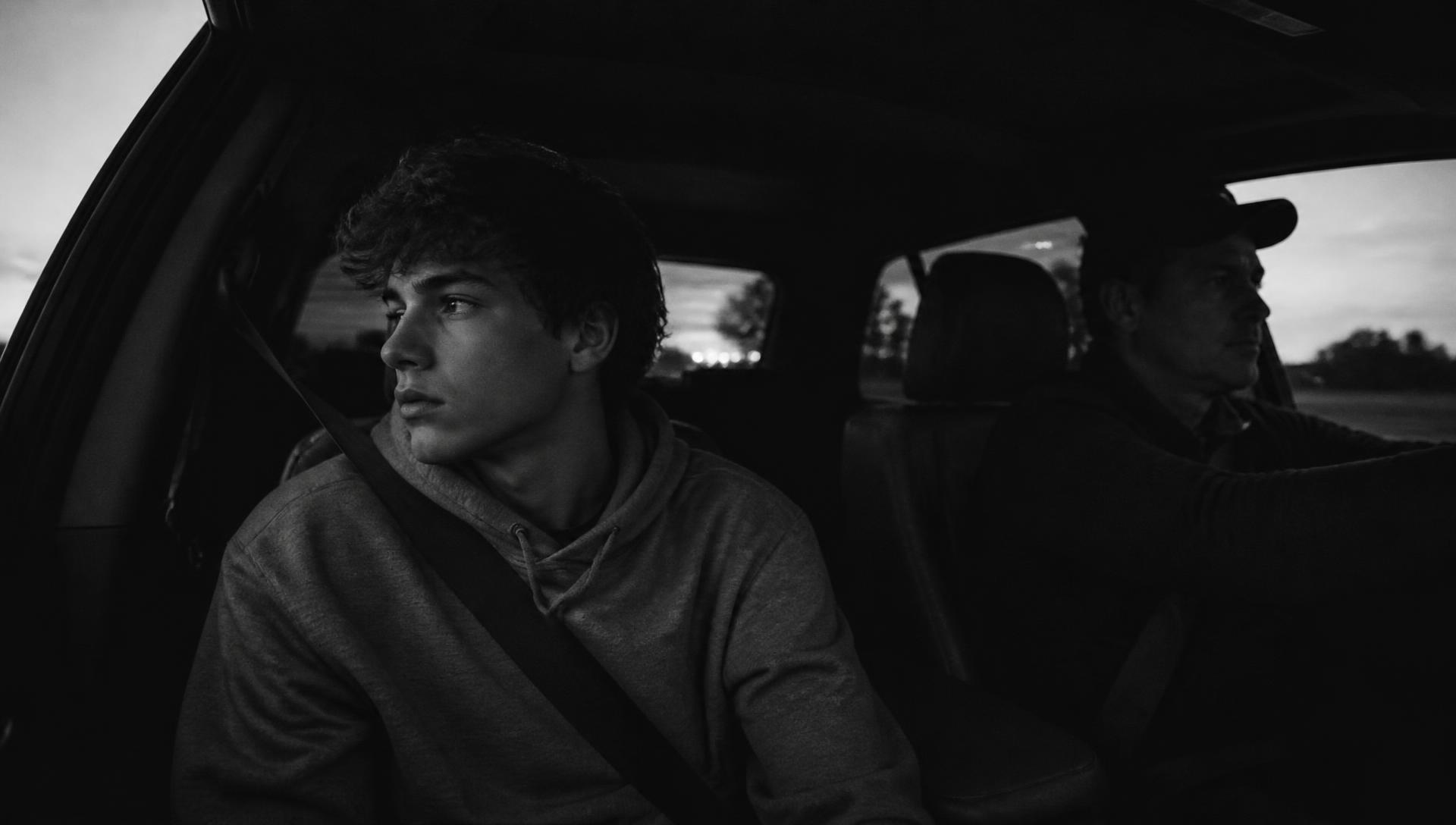 A parent driving home at dusk while their teenage athlete looks quietly out the window