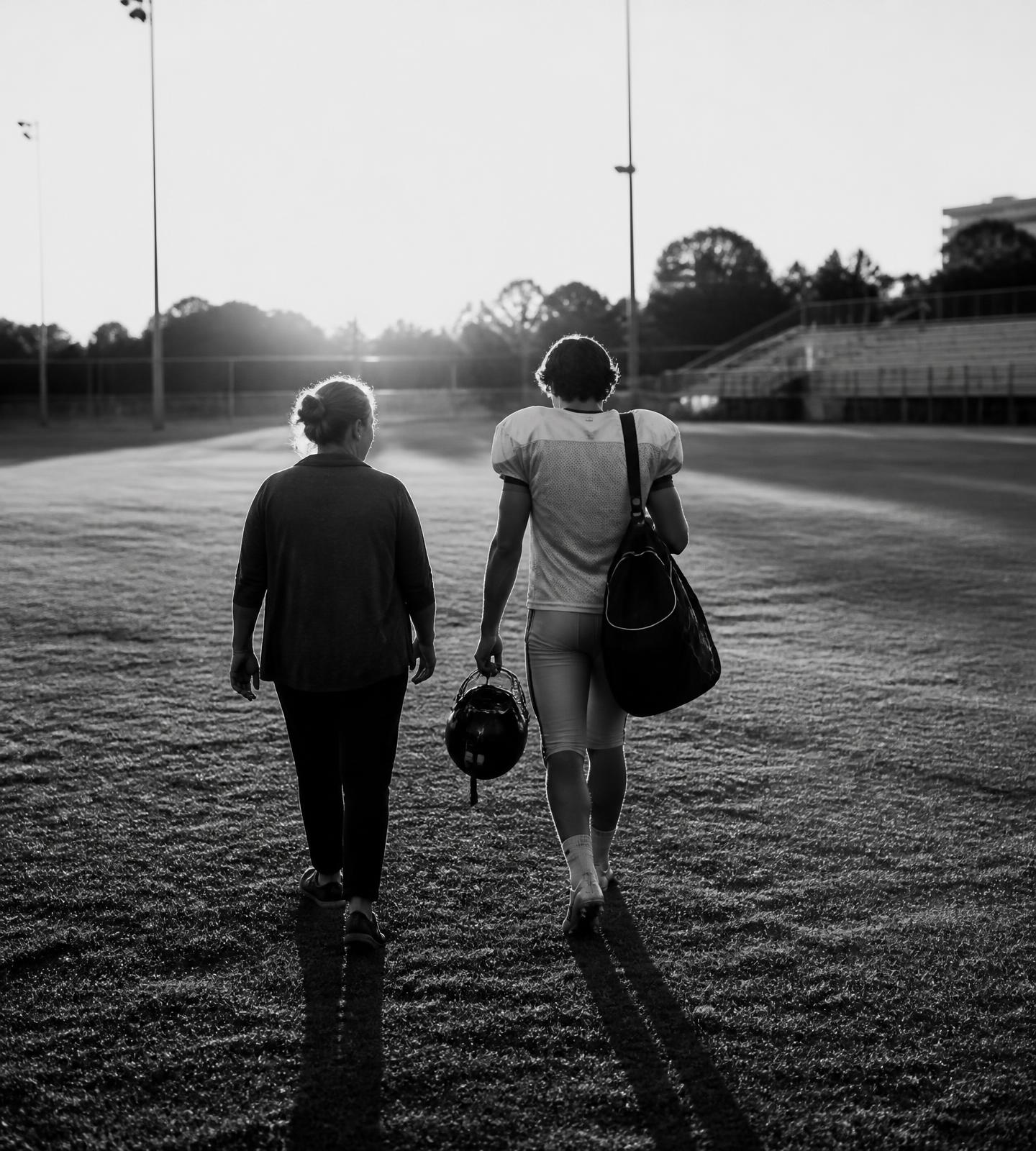 A parent and their athlete walking off the field together after a game